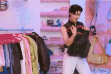 a man is standing in front of a rack of clothes holding a black shirt .