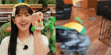 a woman is smiling and holding a stuffed animal in her hand next to a picture of a dog wearing a hat .