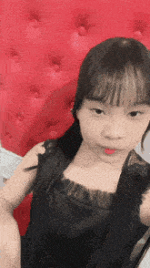 a young girl sitting in front of a red couch