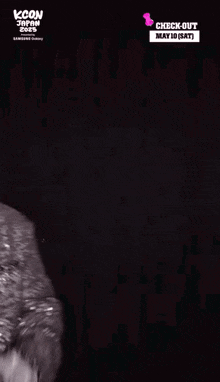 a man in a sequined jacket stands in front of a black background with a check-out date of may 10
