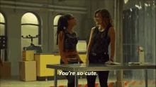 two women are standing next to each other and one of them is saying you 're so cute .