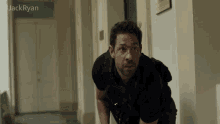 a man in a black shirt is in a hallway with the name jack ryan above him