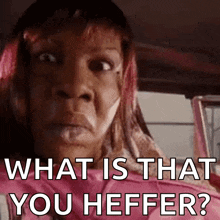 a woman with pink hair is sitting in a car and says what is that you heffer .