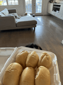 a bunch of rolls in a styrofoam container in front of a couch