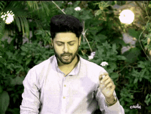 a man in a white shirt is standing in front of a lush green background with the word orilia written on the bottom