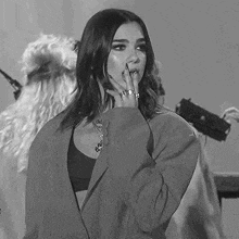 a black and white photo of a woman wearing a jacket and a bra .