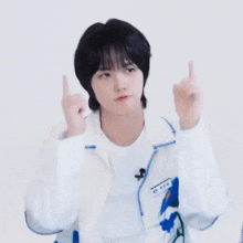 a person wearing a white jacket with blue flowers on it is making a heart shape with their hands