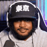 a man with a beard wearing headphones and a hat that says tokyo