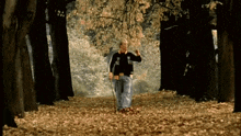 a man is walking through a forest covered in leaves