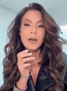 a woman with long hair is wearing a leather jacket and a bracelet