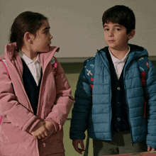 a boy and a girl are standing next to each other and the girl is wearing a pink jacket