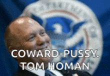 a man in a suit and tie with the words coward-pussy tom homan on the bottom