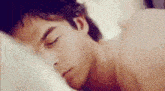 a man is sleeping in a bed without a shirt on .
