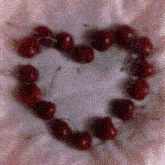 cherries arranged in a heart shape on a white surface