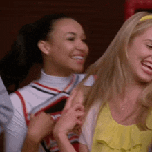 two cheerleaders are smiling and laughing together