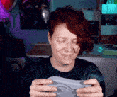 a woman with red hair is smiling while holding a video game controller in her hands