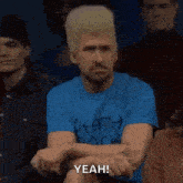 a man with a wig on his head is sitting in a crowd with his arms crossed .