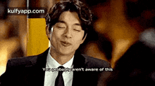 a man in a suit and tie is making a funny face while talking to someone .