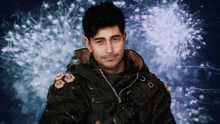a man stands in front of a fireworks display and looks at the camera with a smile on his face