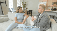 a man and a woman are sitting on a couch with the man saying " against you to be honest "