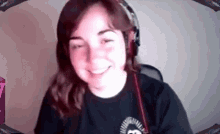 a woman wearing headphones and a black shirt is smiling while looking at the camera .
