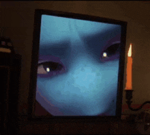 a picture of a woman 's face is on a television next to a lit candle