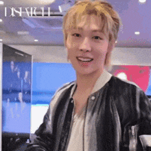 a man wearing a black leather jacket and a white shirt is smiling