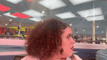 a woman with curly hair is sitting in a room with a red light on the ceiling