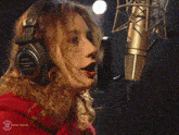 a woman wearing headphones singing into a microphone with the number 3 on the bottom right