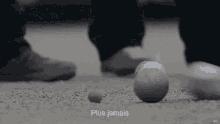 a person standing next to a ball that has the word plus jamais on it