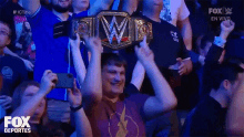 a man is holding a wrestling championship belt in a crowd of people