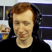 a man with red hair is wearing headphones and making a face .