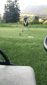 a man swings a golf club at a golf ball on a golf course