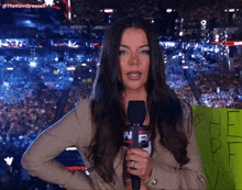 a woman holding a microphone in front of a crowd with a sign that says " the bf vs "