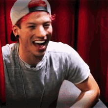 a man wearing a baseball cap and a gray shirt is laughing .