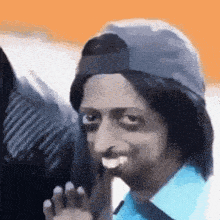 a man wearing a hat and a blue shirt is making a face