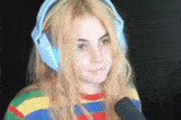 a woman wearing headphones and a striped shirt is smiling and holding a microphone .