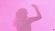 taylor swift is dancing on stage in front of a pink background while wearing a black dress .
