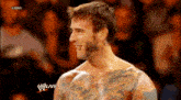 a man with a lot of tattoos on his chest is standing in front of a crowd and the words raw are on the bottom