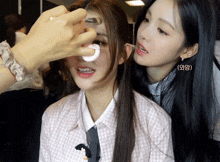 a woman applying makeup to another woman 's face with a sponge