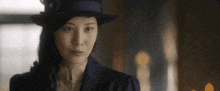 a woman wearing a hat and a suit looks to the side