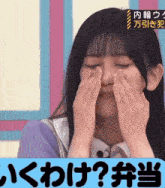 a girl is covering her face with her hands in front of a sign that says " ? "