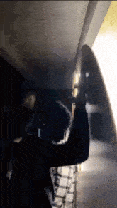 a man in a plaid shirt is holding a skateboard in a dark room .