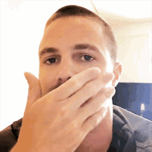 a man covering his mouth with his hand while looking at the camera