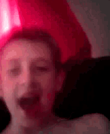 a close up of a person 's face with a red light in the background .