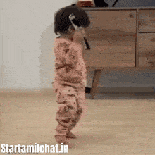 a baby is standing on its feet in a living room .