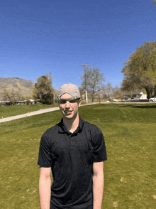 a man wearing sunglasses and a hat is standing in a golf course