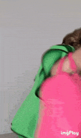 a woman in a green jacket is holding a bright pink bag