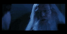 a man with long white hair and a beard is standing in the dark .