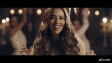 a woman is standing in front of a group of people dancing in a video .